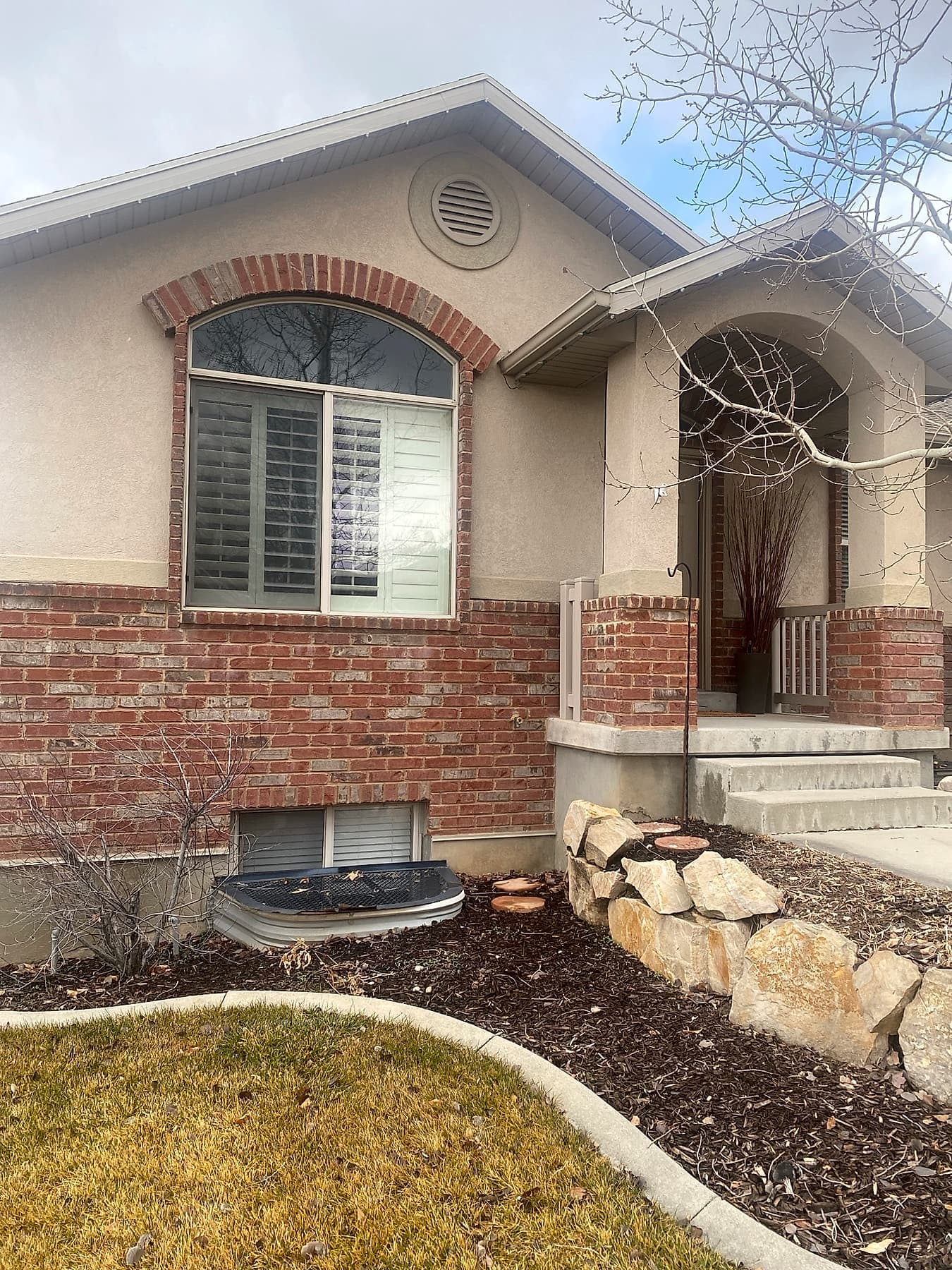 Arched-top window with grids set in a brick surround near a home's front entry
